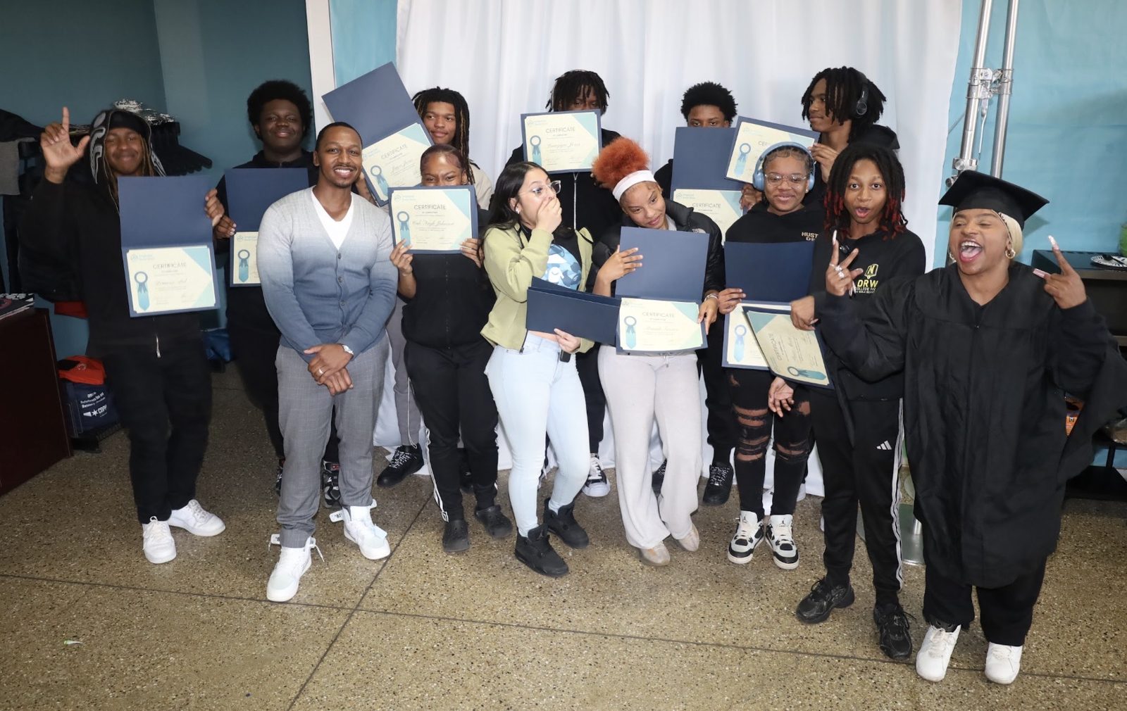 CyberSecure Teens graduates celebrating with their certificates of completion, one wearing a cap and gown